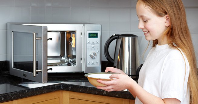 Young girl using microwave